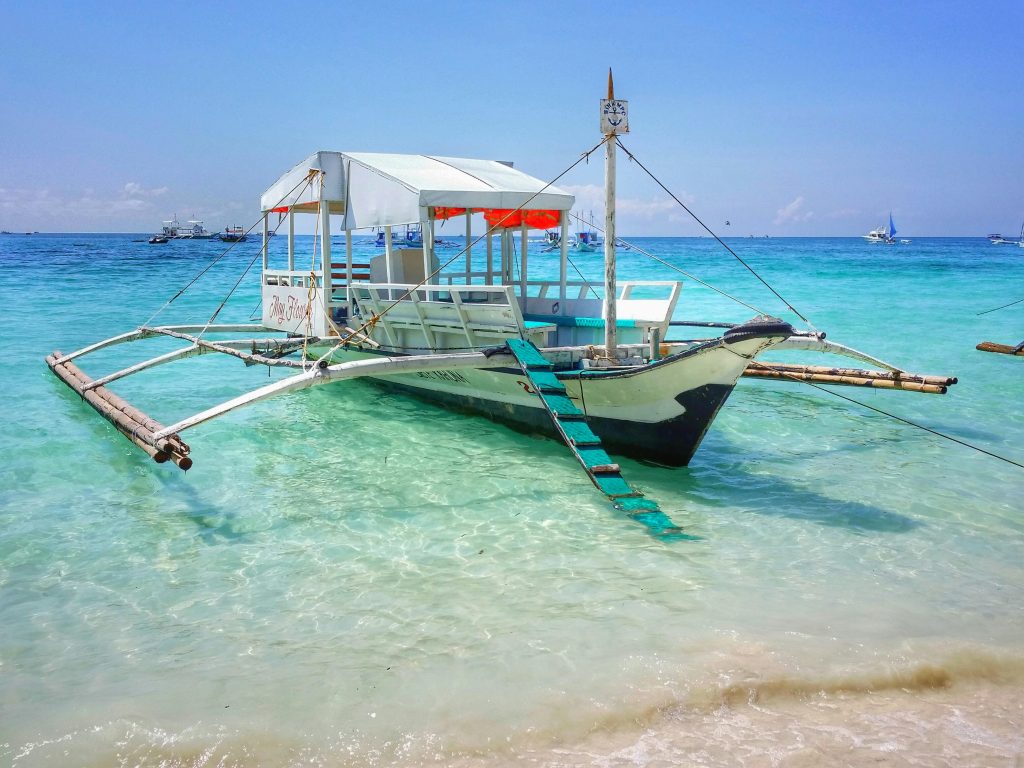 A traditional Filipino boat anchored on the turquoise waters of a stunning beach in the Philippines.